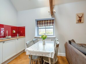 Une cuisine avec une table à manger, des chaises et une fenêtre donnant sur un beau paysage.