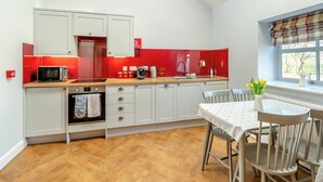 Una cocina moderna con armarios blancos, salpicadero rojo y encimera de madera.