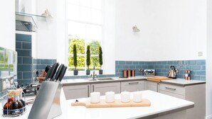 Een moderne keuken met een centraal eiland, een kookplaat en een raam met planten.
