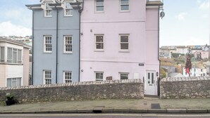 Un edificio de dos pisos con un muro de piedra en la parte delantera, con varias ventanas y una puerta.