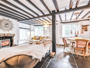 A modern living room with exposed beams, a fireplace, a sofa, and a dining area with a table and chairs. - 2 bedroom accommodation in Milton Combe, near Yelverton (Milton Combe, near Yelverton)