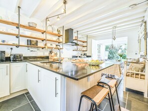 Eine moderne Küche mit einer großen Kochinsel, weißen Schränken und Blick zum Wohnbereich.