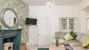 Un salon avec une cheminée, un canapé, un téléviseur et un tapis vert.