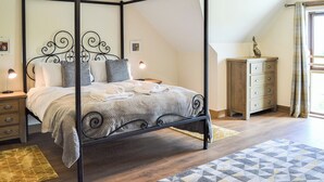 Una cama con dosel sobre estructura de metal, una mesita de noche de madera, un aparador y una alfombra estampada.