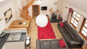 Ein geräumiger Wohnbereich mit Treppe, Kamin, Sofa und Küchenzeile.