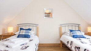 Ein Schlafzimmer mit zwei Betten, jeweils mit einem Holz-Kopfteil, einem kleinen Spiegel an der Wand und einem Holzboden.
