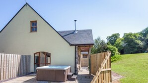 A house with a hot tub, a wooden fence, and a grassy yard.