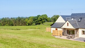 A house with a stone exterior, a sloped roof, and a small patio with outdoor seating.