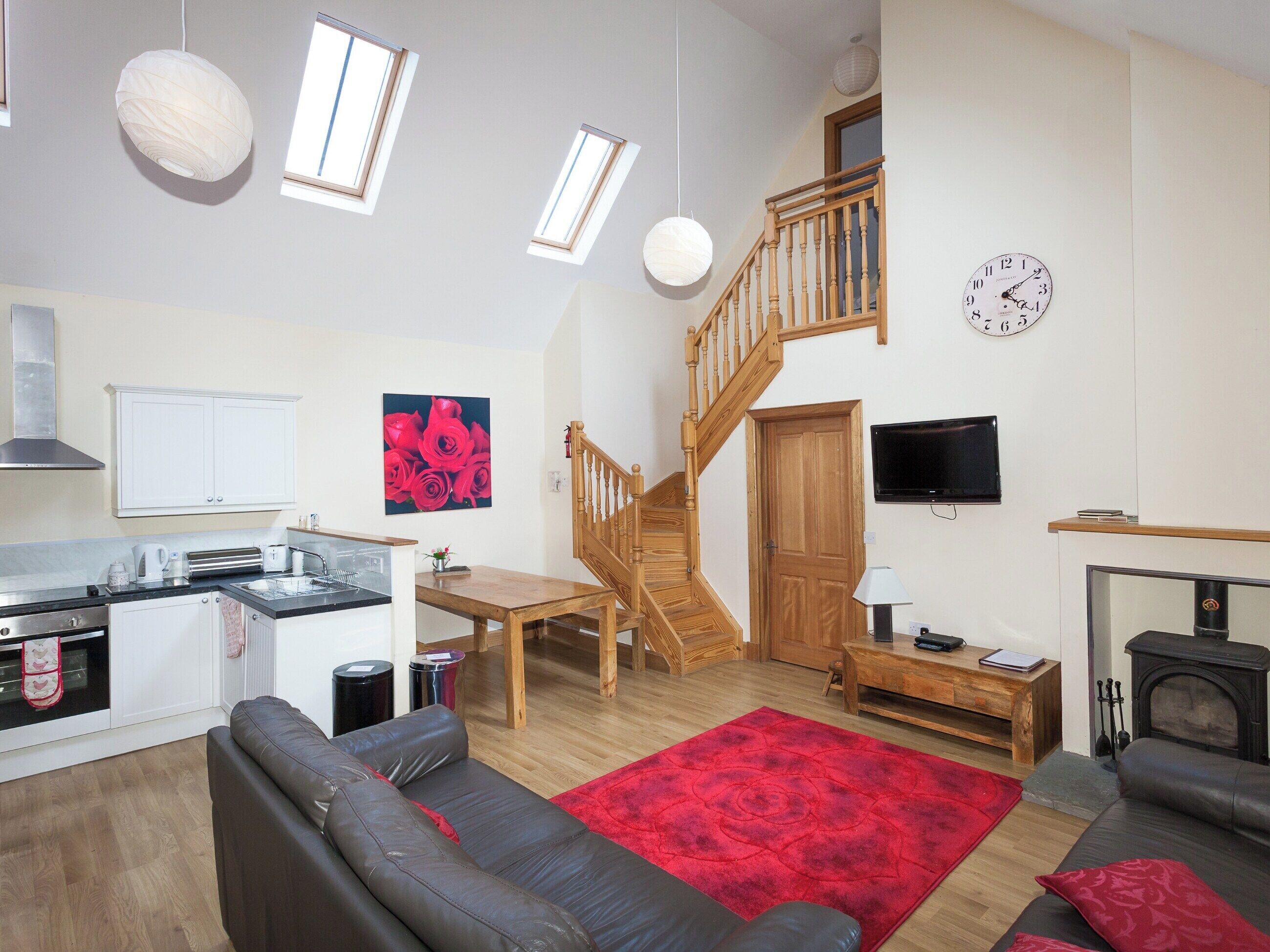 A spacious living area with a kitchen, a dining table, a sofa, a fireplace, and a staircase.