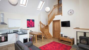 A spacious living area with a kitchen, a dining table, a sofa, a fireplace, and a staircase.