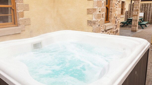 Ein Whirlpool in einer Außenanlage mit Steinwänden und Holzmöbeln.