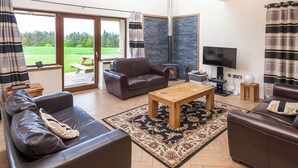 Ein modernes Wohnzimmer mit Ledersofas, einem Holztisch und einem Kamin aus Stein.
