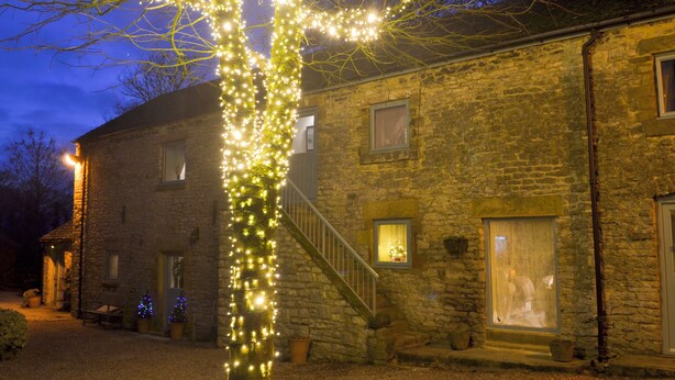 Un bâtiment en pierre avec un escalier et un arbre décoré de guirlandes lumineuses.