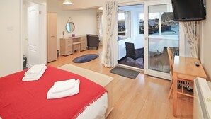 Een hotelkamer met een bed, een bureau, een stoel, een televisie en uitzicht op het exterieur.