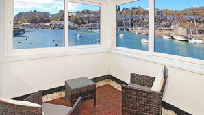 Een terras met rieten meubels en uitzicht op een haven met boten.