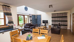 Ein geräumiger Wohnbereich mit Esstisch, Sofas und Kamin.