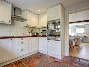 A modern kitchen with white cabinets, a stainless steel range hood, and a tiled backsplash. - 3 bedroom accommodation in Stiffkey (Stiffkey)