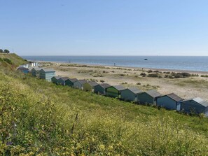 Eine Reihe von Strandkörben entlang eines sandigen Strandes mit freiem Blick auf das Meer.