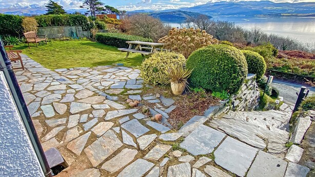 Un patio de piedra con vistas a montañas y un lago.