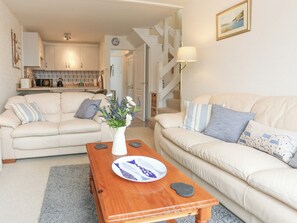 A living room with two sofas, a coffee table, and a kitchen in the background. - 2 bedroom accommodation in Porthmadog (Porthmadog)