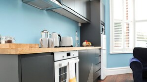 Een moderne keuken met een inbouwoven, een koffiezetapparaat en een waterkoker op het aanrecht.