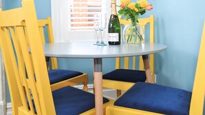 Een eettafel met een fles champagne, een glas en een vaas met bloemen.