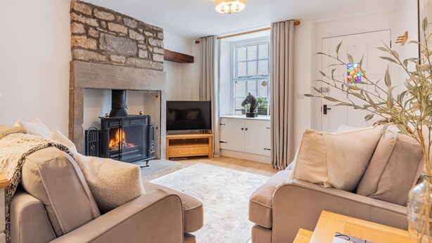 Ein gemütliches Wohnzimmer mit Kamin, Fernseher und bequemen Sitzmöglichkeiten.