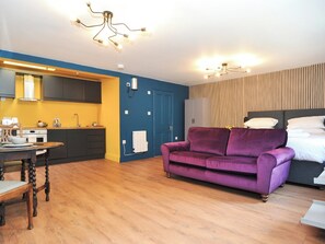 A modern apartment with a kitchen, a purple sofa, and a bed with white bedding. - Beale Apartment - UKC6338 (Cheltenham)