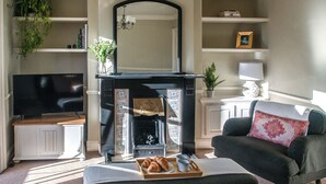 Ein Wohnzimmer mit Kamin, Fernseher und einer Couch mit Zierkissen.