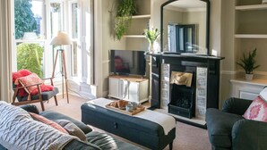 Ein Wohnzimmer mit Kamin, Fernseher und Sitzgruppe.