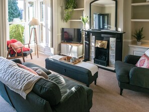 Ein Wohnzimmer mit Kamin, Fernseher und Sitzgruppe.