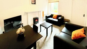 Ein Wohnzimmer mit Fernseher, Kamin, Sofa und Couchtisch.