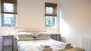 Een slaapkamer met een bed, twee nachtkastjes met lampen, een raam met uitzicht en een radiator.