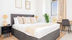 Ein modernes Schlafzimmer mit einem großen Bett, Nachttischen, einem Schreibtisch und Blick ins Freie.