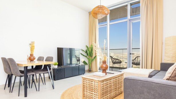 Ein modernes Wohnzimmer mit Essbereich, einer Couch, einem Fernseher und einem großen Fenster mit Aussicht.