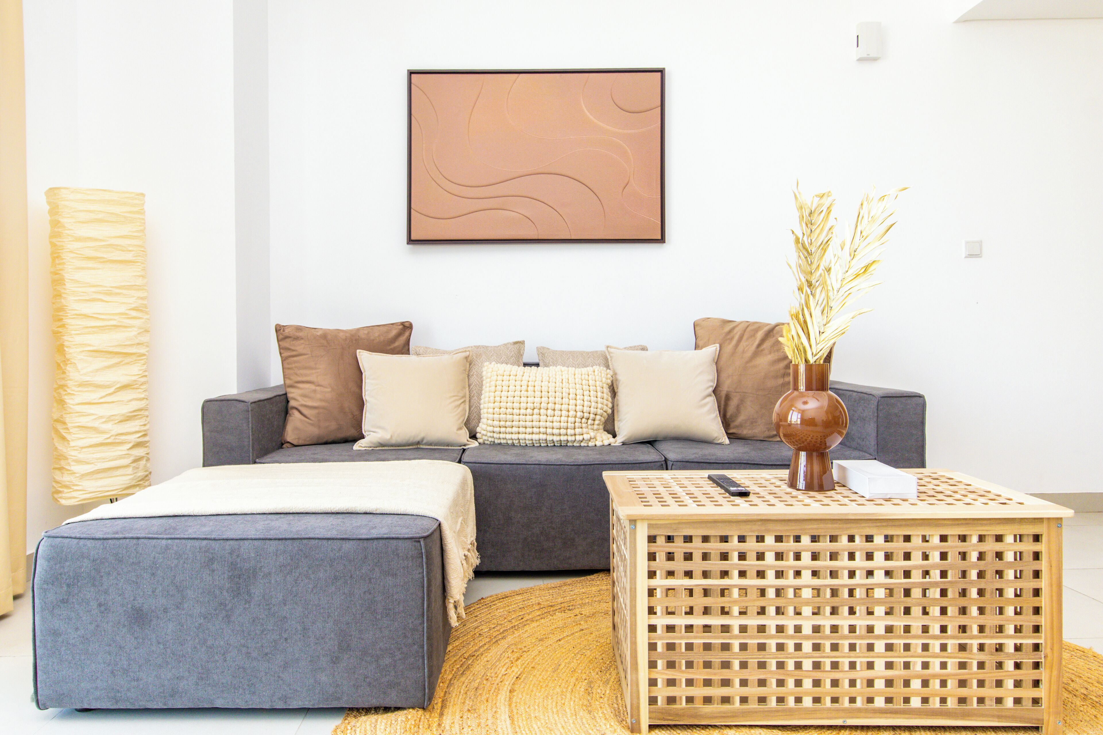 A modern living room with a grey sofa, a wooden coffee table, and a large abstract painting on the wall.
