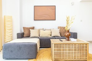 A modern living room with a grey sofa, a wooden coffee table, and a large abstract painting on the wall. - Bloomfields 1br Elegant Escape Pulse (Dubai)