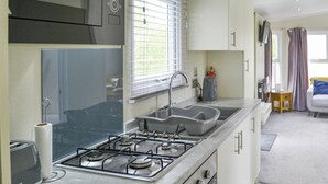 Una cucina compatta con fornello a gas, lavandino e tostapane.