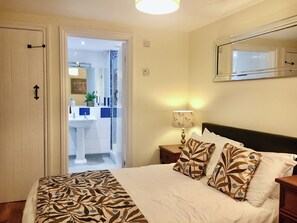 A bedroom with a bed, pillows, a nightstand, a lamp, and a mirror on the wall. - A perfect retreat for couples or families to really kick back, relax and enjoy. (Wooton Fitzpaine, near Charmouth)