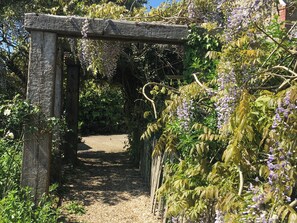 A wooden archway leading into a garden with a gravel path. - A perfect retreat for couples or families to really kick back, relax and enjoy. (Wooton Fitzpaine, near Charmouth)