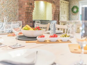 A dining table set with a bowl of fruit, glasses, and a decorative book stand. - 5 bedroom accommodation in Grayrigg, near Kendal (Grayrigg, near Kendal)