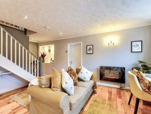A living room with a sofa, a TV, a staircase, and a wall-mounted picture.