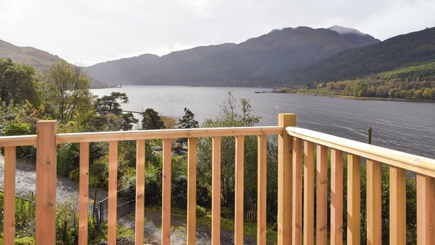 A wooden deck overlooking a lake with mountains in the background.