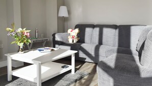 A living room with a white coffee table, grey sofa, and a lamp.