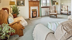 A cozy living room with a fireplace, a sofa, a chair, and a small table. - 2 bedroom accommodation in Troon, near Ayr (Troon, near Ayr)