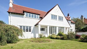 A two-story white house with a red-tiled roof, multiple windows, and a well-maintained garden. - 2 bedroom accommodation in Troon, near Ayr (Troon, near Ayr)