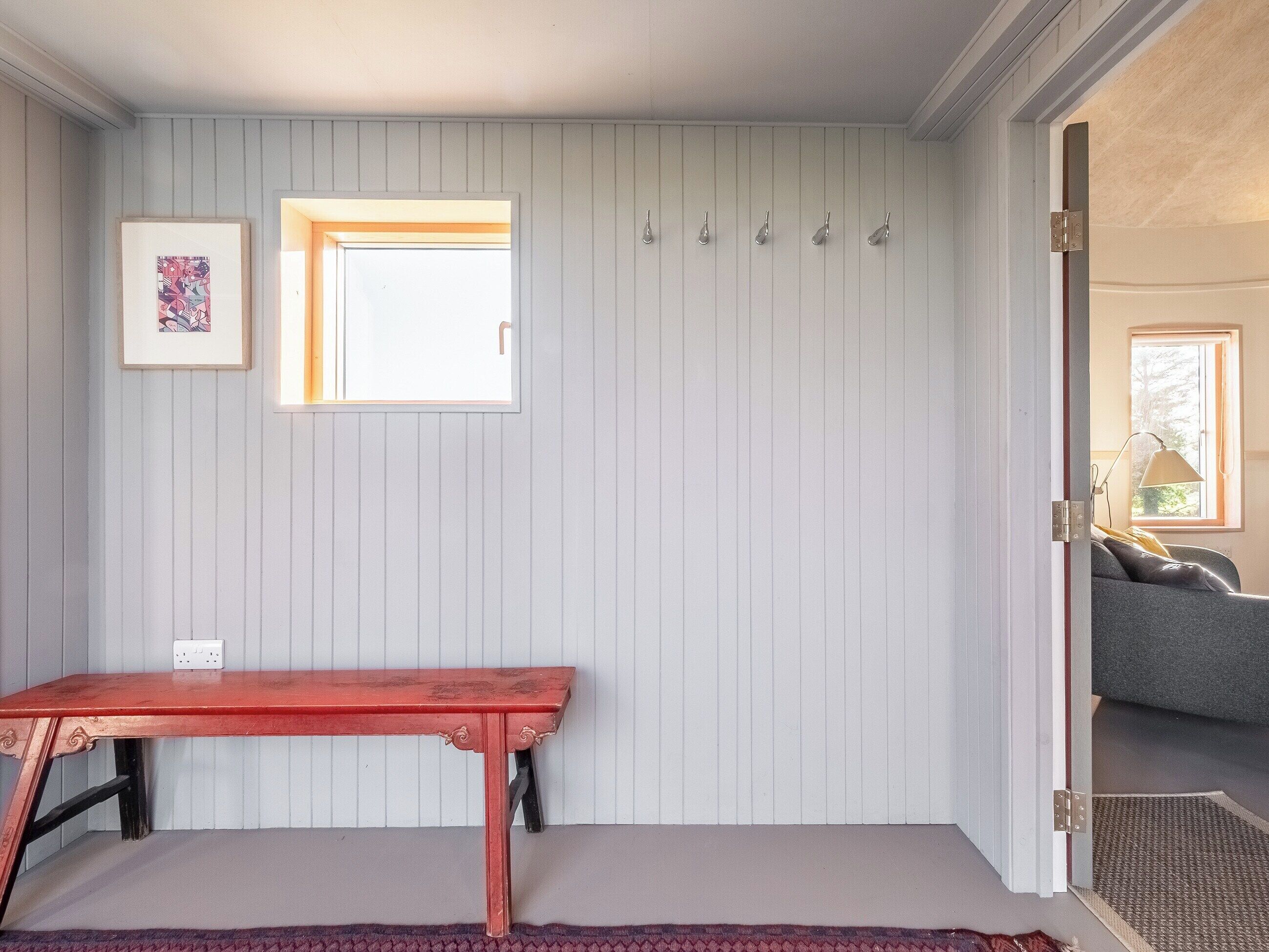 A room with a red table, a window, a door, and a light fixture.
