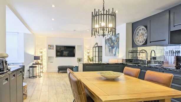 A modern kitchen with a dining area, featuring a wooden table, chairs, and a chandelier. - 2 bedroom accommodation in Seaview (Seaview)