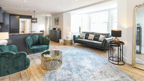 A spacious living room with a green sofa, a coffee table, and a large mirror. - 2 bedroom accommodation in Seaview (Seaview)