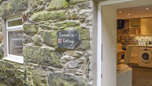 Un cottage in pietra con un cartello che riporta 'Snowdon Cottage'.